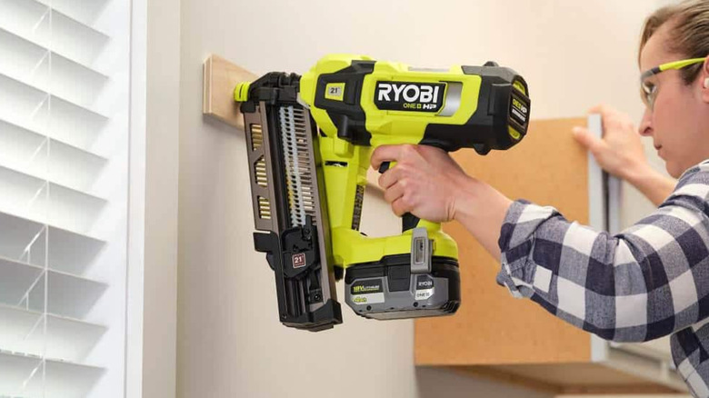 A person uses the Ryobi One+ HP Brushless AirStrike Framing Nailer on a wall.