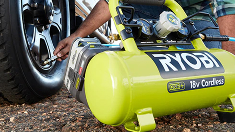A person using a Ryobi air compressor to inflate a tire