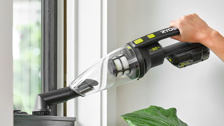 A person vacuuming a window with a hand vacuum