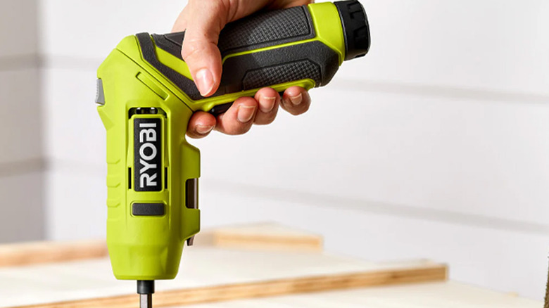 A person using a Ryobi cordless screwdriver on a desk drawer