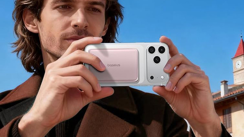 A man taking a picture with a smartphone and a Baseus battery.
