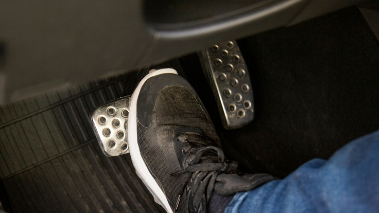 Foot pushing down on a brake pedal