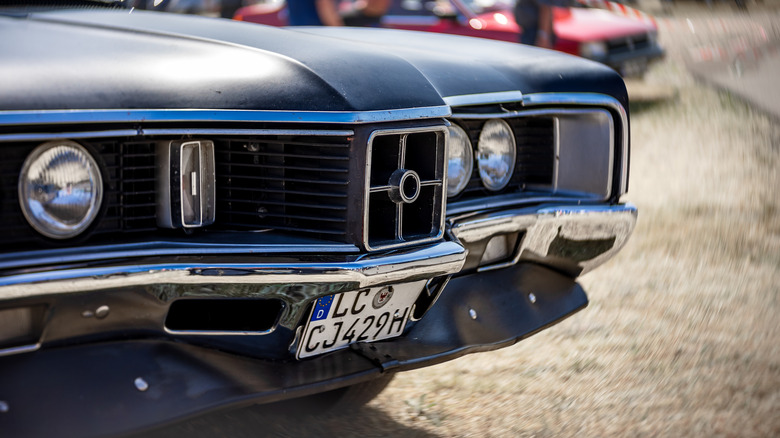 A gray 1970 Mercury Cyclone Spoiler parked on gravel and sand, with the classic "W" grill prominently shown.