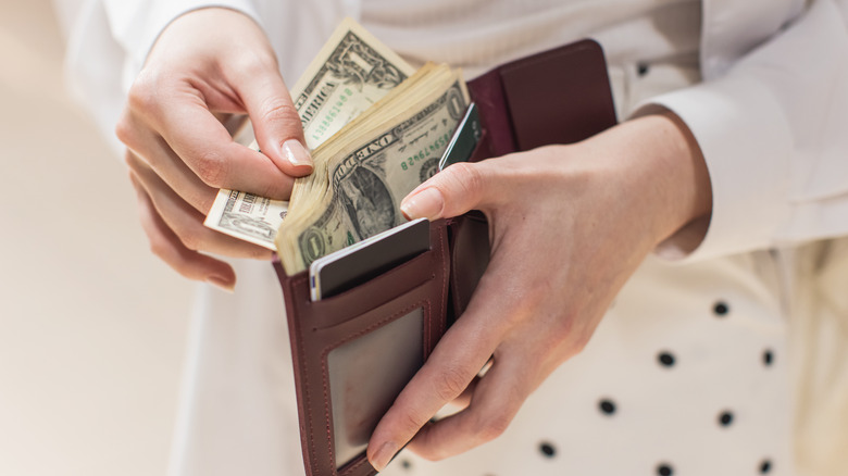 A person pulling American dollars out of a wallet