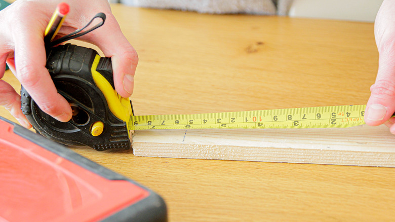 Extending tape measure on piece of wood