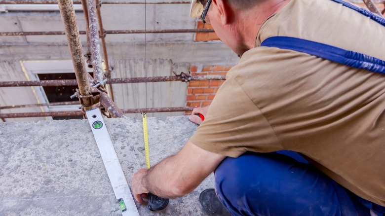 worker using tape measure and pencil