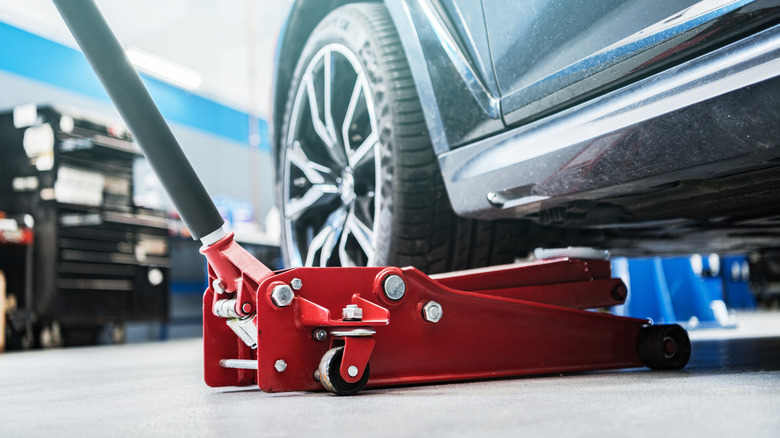 A heavy-duty floor jack lifting a car.