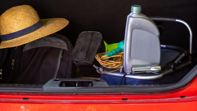 Car trunk packed with a hat, a flashlight, car oil, and other essentials.
