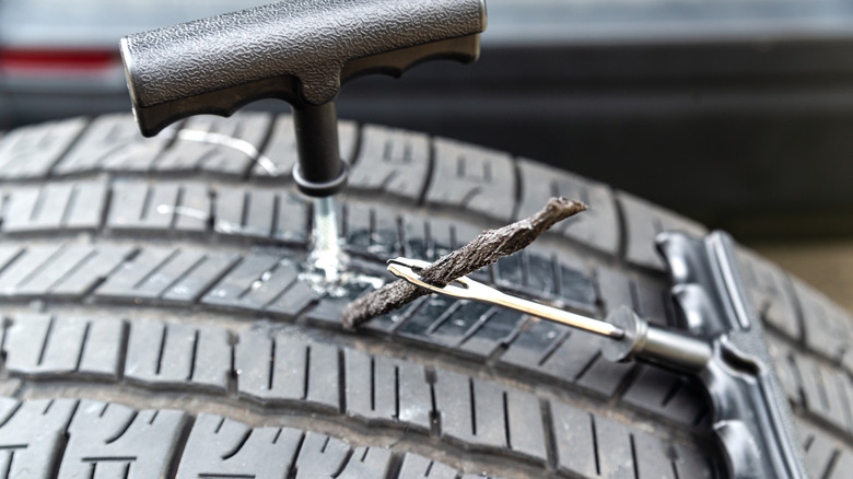 Tire repair kit being used for repairing punctured tire.