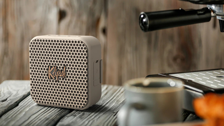 Light brown Klipsch mini speaker on a surface next to an espresso machine and coffee cup