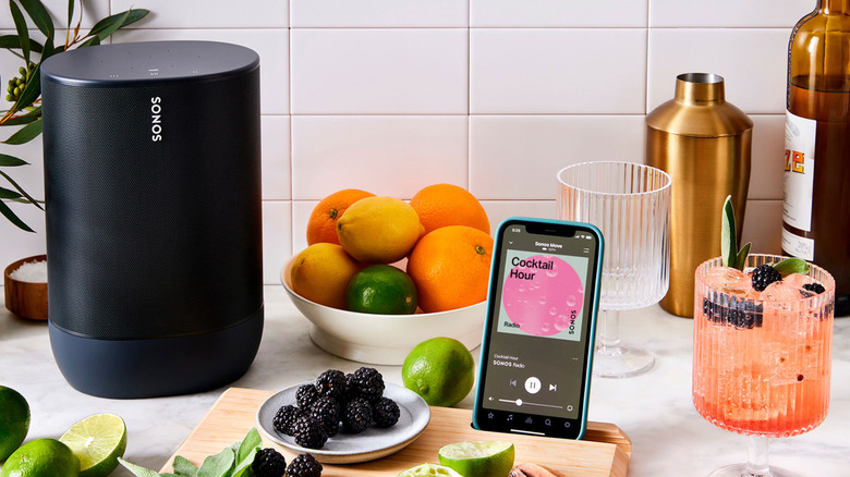 Sonos speaker on a kitchen countertop with various cocktail ingredients and a phone showing a cocktail hour playlist