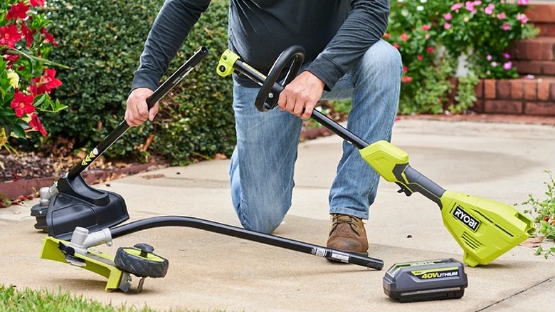 Man assembling a Ryobi string trimmer outside the house.
