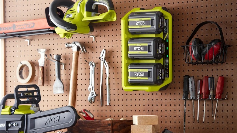 Several Ryobi tools and batteries mounted onto a work board along with smaller hand tools.