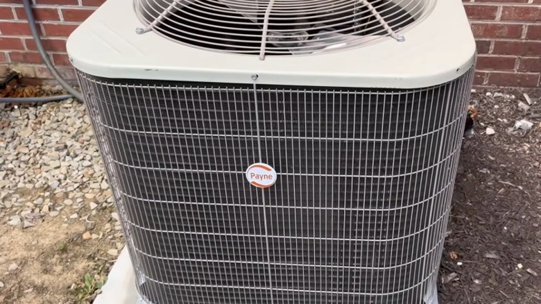 Payne air conditioner next to a red brick wall