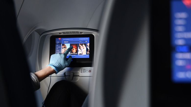 A person taping on Delta Air Lines' IFE touchscreen.