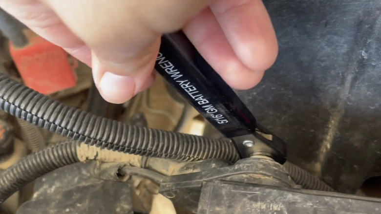 Person using a ratchet wrench on a side-post battery