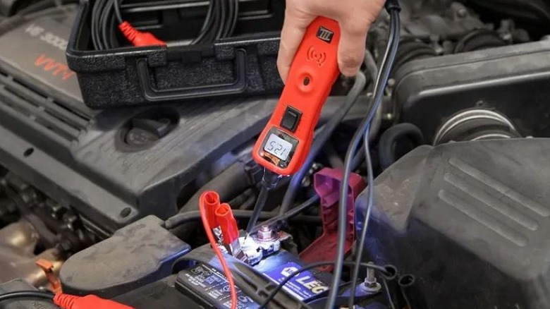 Person testing a battery with a Power Probe inside a vehicle