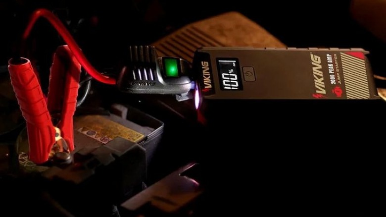 Portable jump starter connected to vehicle battery with clamp