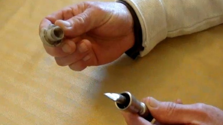 person with a disconnect tool in one hand and a fuel line in the other