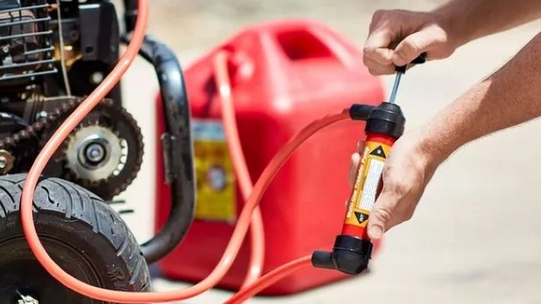 Person filling a generator from a gas container using a hand pump