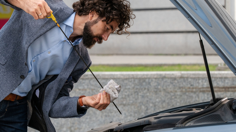 A person wiping their car's dipstick with a cloth