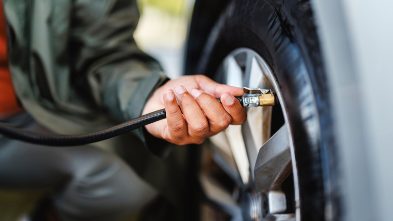 A person measuring tire pressure with a gauge
