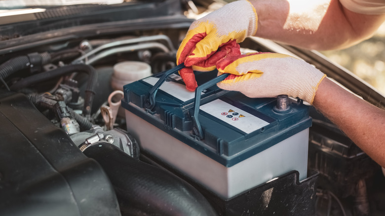 A person removing a car battery