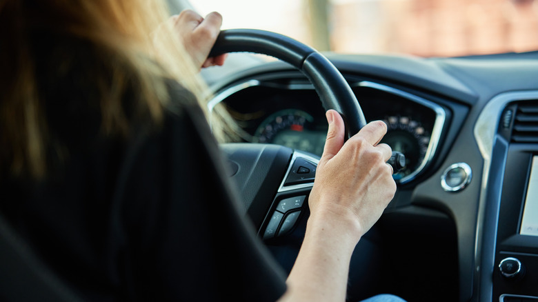 A driver with the steering wheel and dashboard partly visible