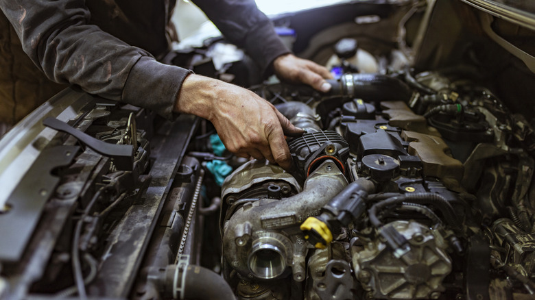 A mechanic looking at an engine in a car.