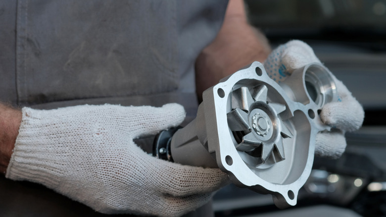 A mechanic holding a water pump.