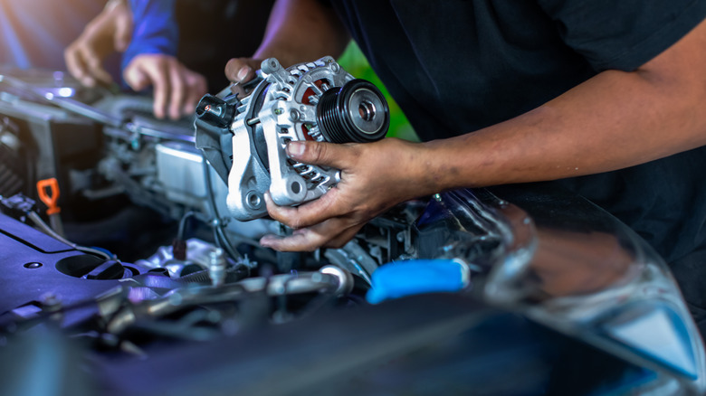 A mechanic holding an alternator.