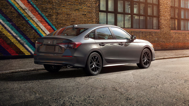 Silver Honda Civic sedan parked on a gray surface with brick wall building behind