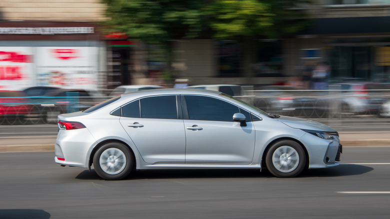 Silver Toyota Corolla driving on a street with the background blurred