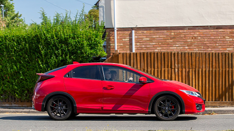 Older red Honda Civic on a road
