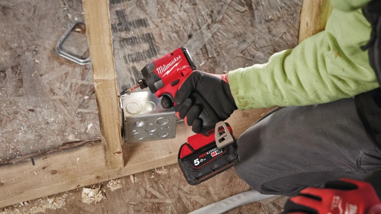 Screwing backbox onto stud with Milwaukee impact driver.