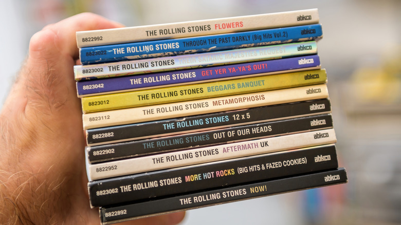 Person holding a stack of Rolling Stones digipak CDs