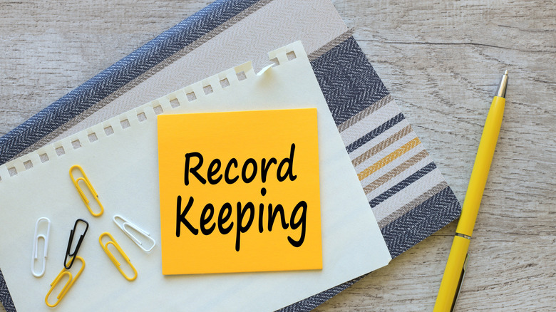 Record keeping written on a yellow sticky note
