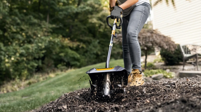 A woman using a DeWalt cultivator on a garden