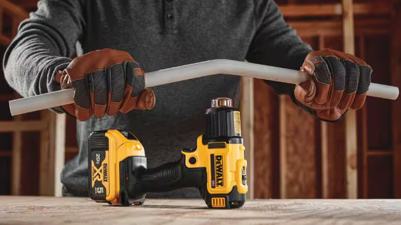 Person bending a pipe over a heat gun