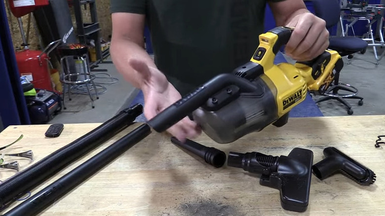 Person holding small vacuum over work table