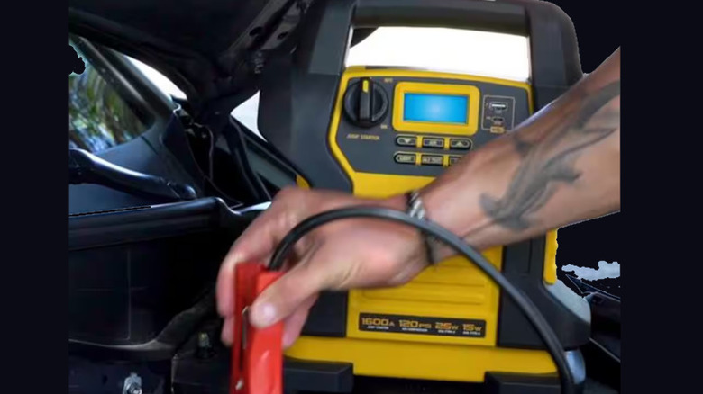 Person attaching jumper cable to car battery