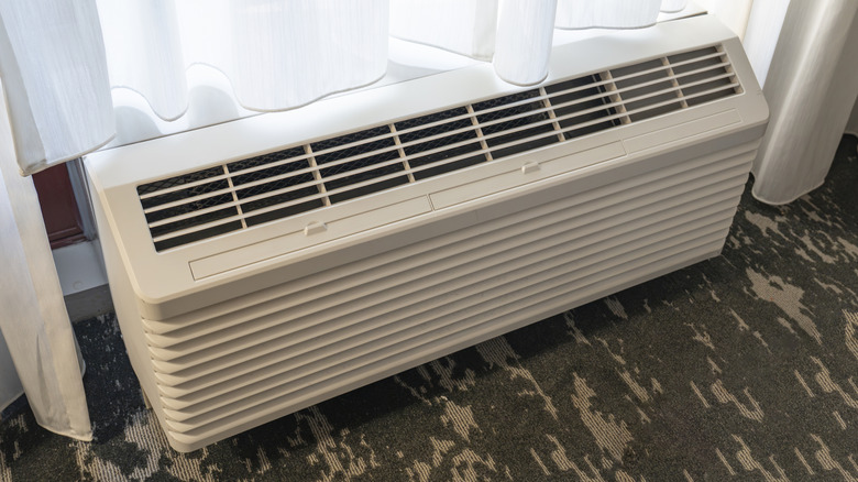 Floor mini split air conditioner inside a hotel room under a window
