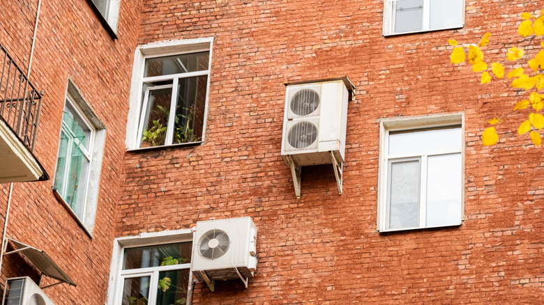 Air conditioner components and windows on the exterior of a brick residential building