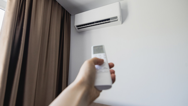Hand pointing a remote at a mini split unit