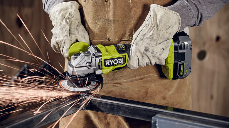 A worker wearing safety gloves using the Ryobi ONE+ HP 18V Brushless Cordless Angle Grinder on steel framework