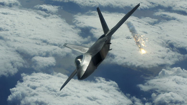 F-22 Raptor jet banking right above clouds and releasing flares