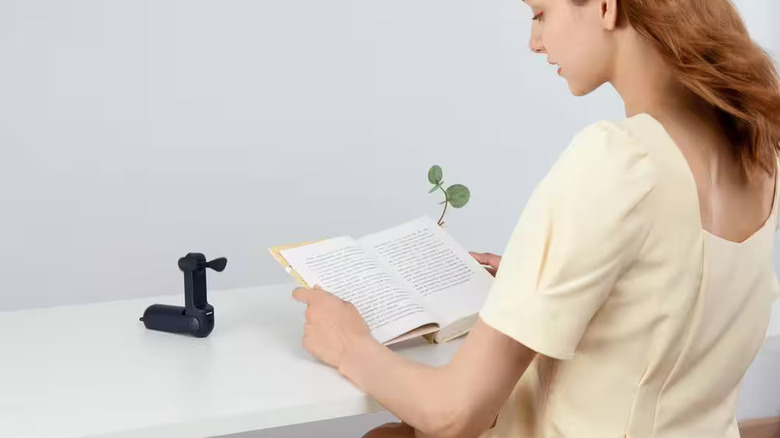 Home Depot portable fan cooling a woman reading a book.