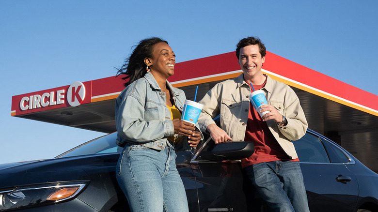 Two people leaning against a car outside a Circle K