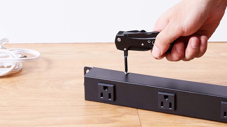 Amazon Basics 15-in-1 Multitool being used on a metal piece