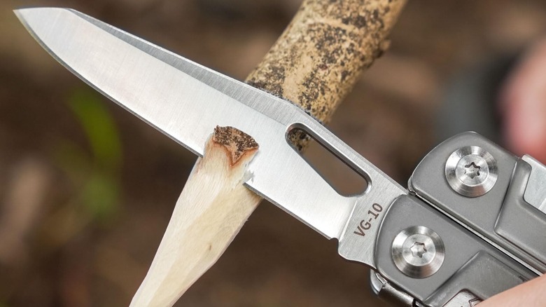 Rocktol Multitool knife being used to sharpen a branch
